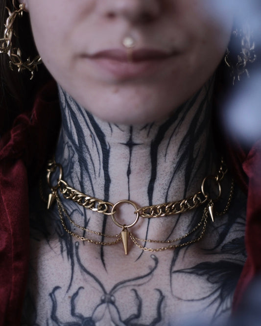 Collier Antarès en acier inoxydable doré avec maillons épais, chaînes drapées et pendentifs pointes.