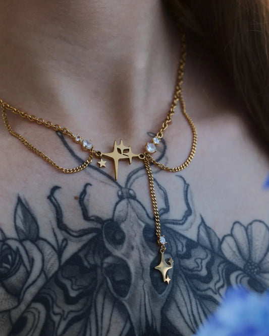 Collier Nuit Filante porté autour du cou, bijou doré orné d’une étoile et chaîne pendante.