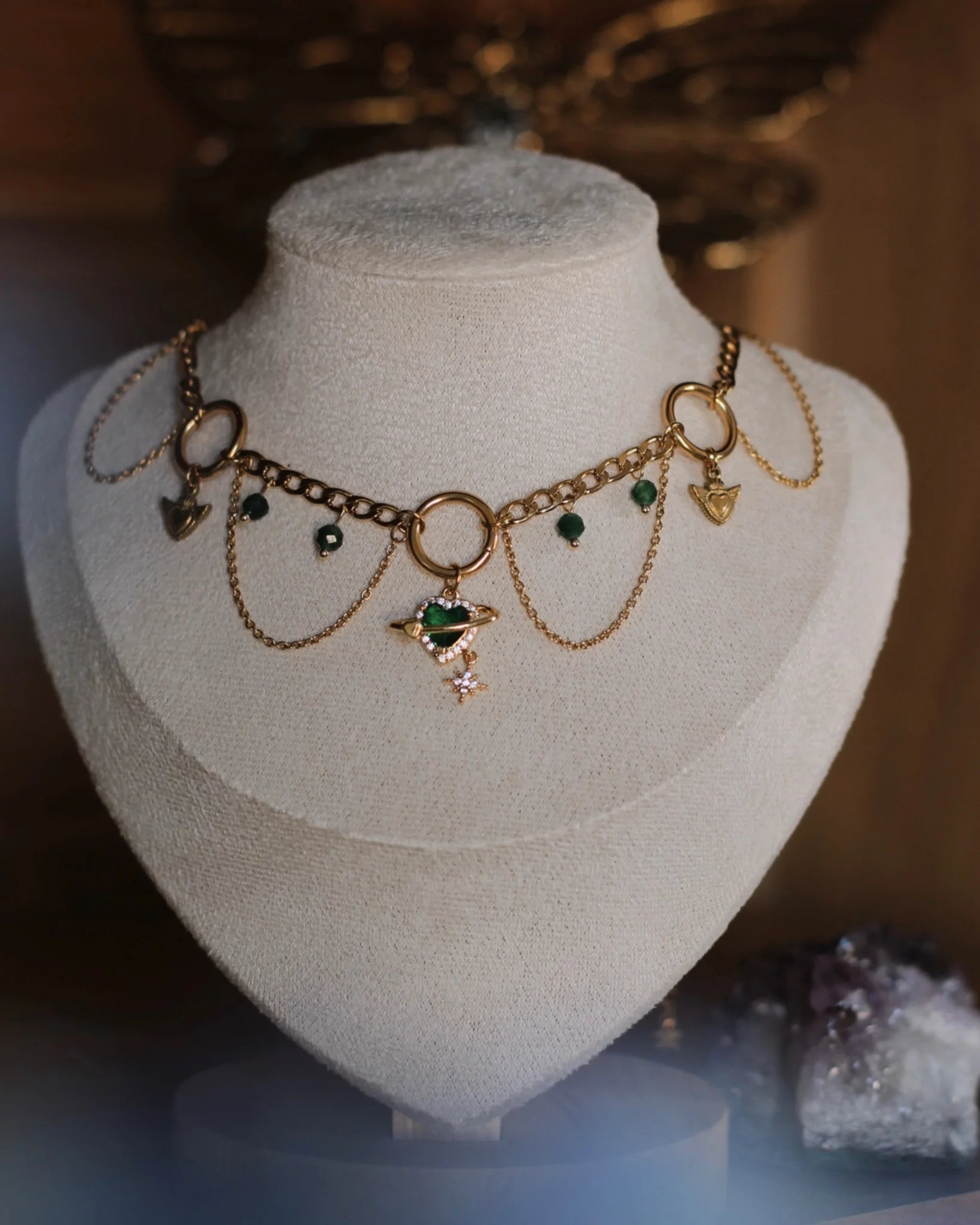 Collier doré Émerys sur présentoir avec pendentif coeur planète et perles vertes