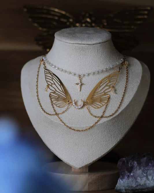 Collier doré L’Ange des Brumes - vue buste sur présentoir, design ailes célestes et chaînes perlées