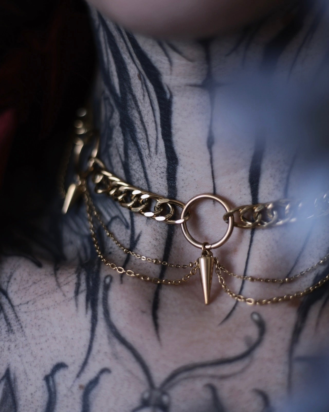Collier Antarès en acier inoxydable doré avec maillons épais, chaînes drapées et pendentifs pointes.