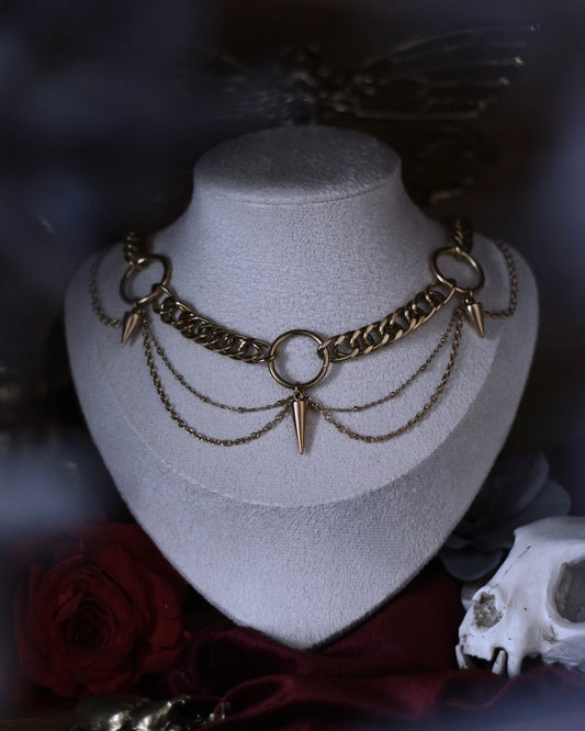 Collier Antarès en acier inoxydable doré avec maillons épais, chaînes drapées et pendentifs pointes.