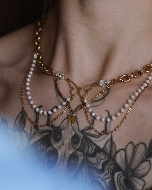 Détail collier Battement Sacré porté - papillon doré, chaînes perlées et pendentif symbolique