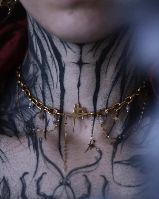 Collier Comète doré avec étoile centrale, chaînes suspendues et breloques étoilées