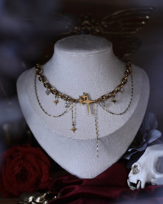 Collier Comète doré avec étoile centrale, chaînes suspendues et breloques étoilées