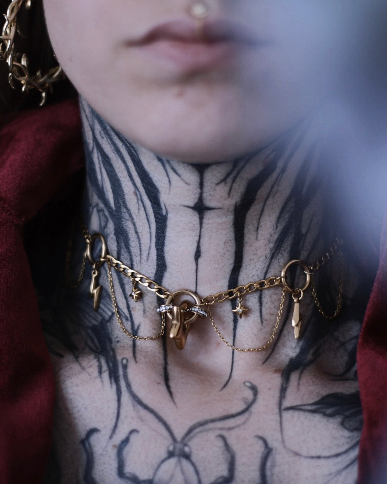 Collier Érèbe doré avec étoiles, éclairs et chaînes suspendues.