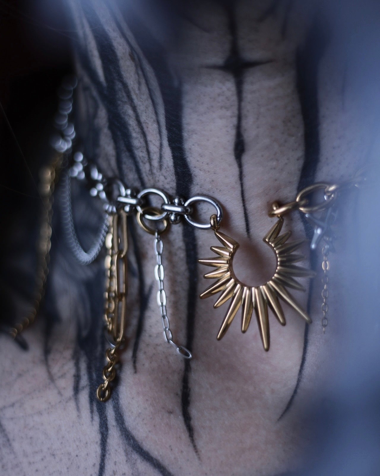 Collier Helios en acier inoxydable doré et argenté avec pendentif soleil, chaînes asymétriques et breloques.