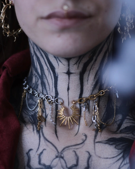 Collier Helios en acier inoxydable doré et argenté avec pendentif soleil, chaînes asymétriques et breloques.