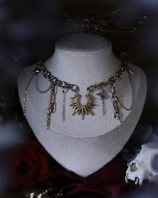 Collier Helios en acier inoxydable doré et argenté avec pendentif soleil, chaînes asymétriques et breloques.