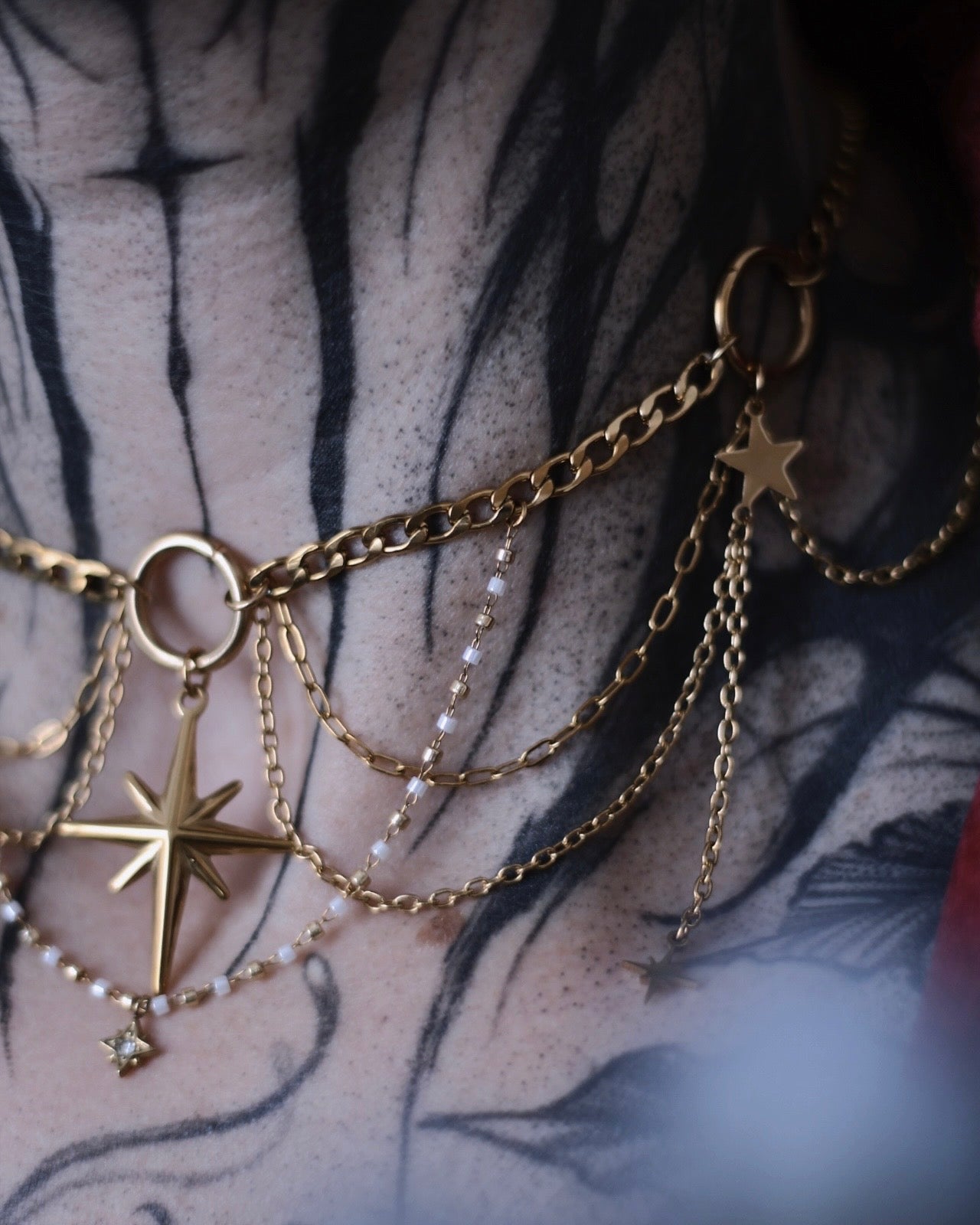 Collier L’Odyssée doré avec étoile centrale, chaînes suspendues et breloques étoilées
