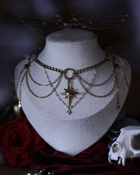Collier L’Odyssée doré avec étoile centrale, chaînes suspendues et breloques étoilées