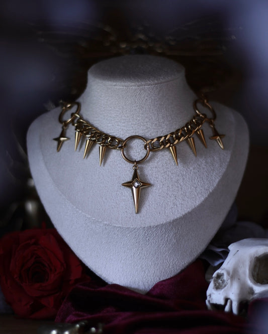 Collier L’Égide doré avec étoile centrale, chaînes et pendentifs en forme de pointes.