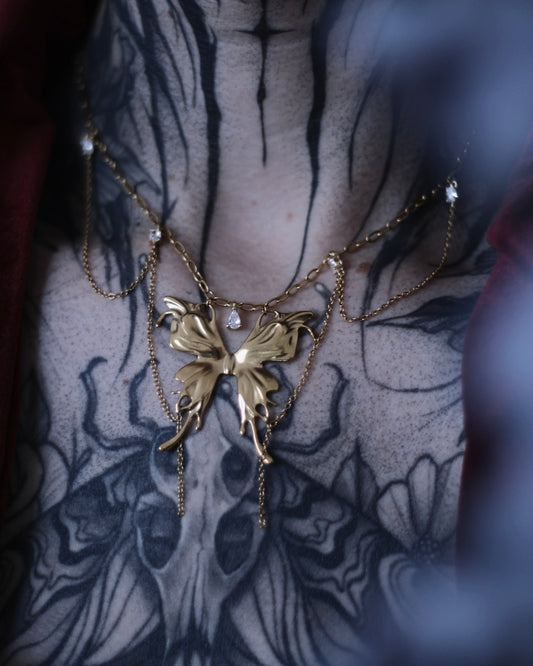 Collier Psyché doré avec pendentif papillon, chaînes suspendues et zircons scintillants.